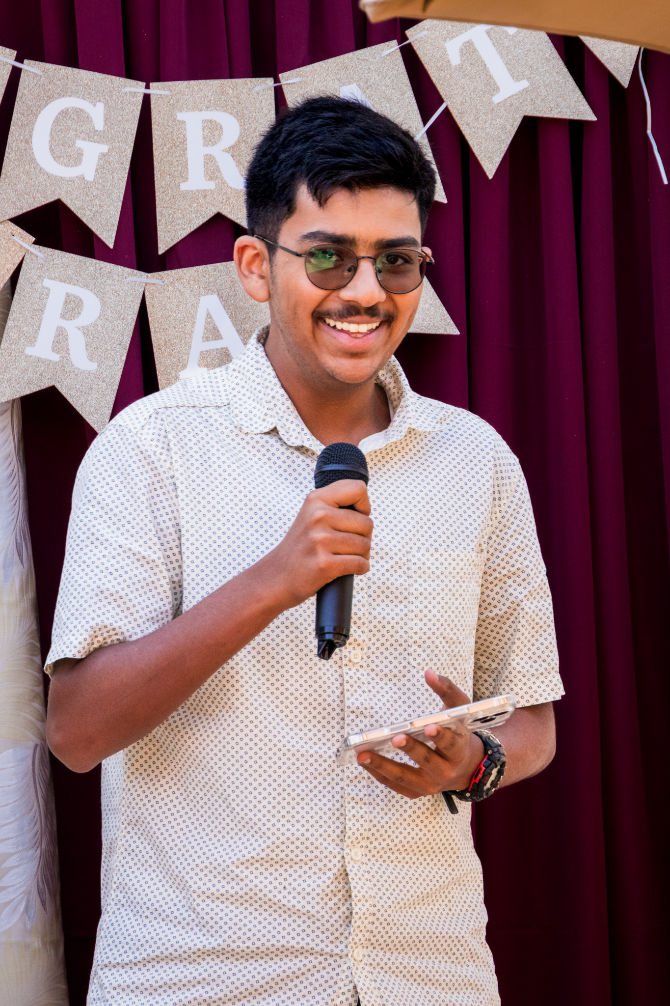 Young man with glasses holding a microphone at an event