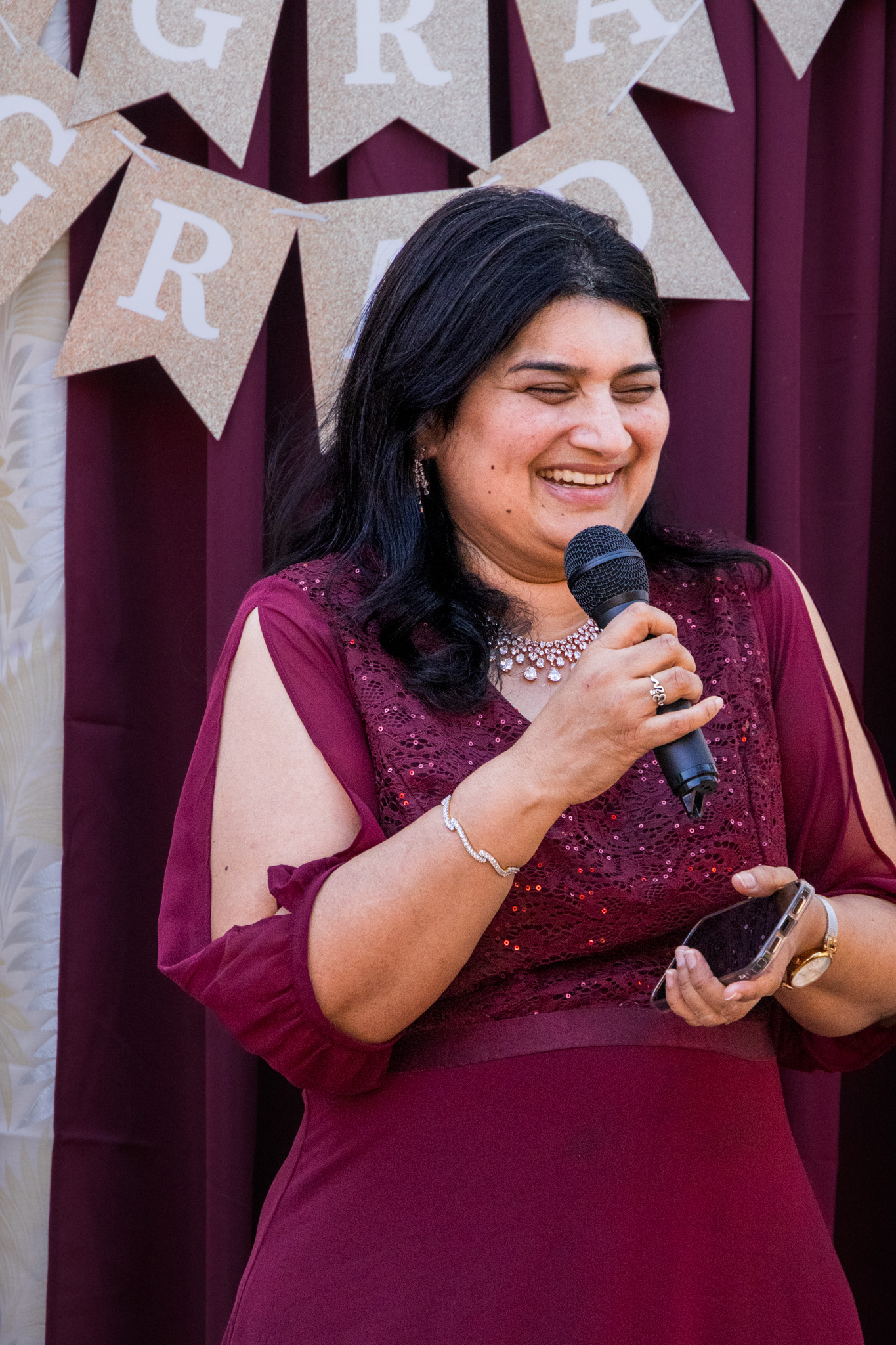 Woman smiling while speaking into a microphone at an event