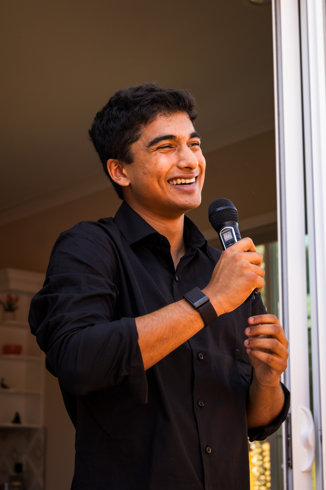 Young man smiling while holding a microphone near a doorway