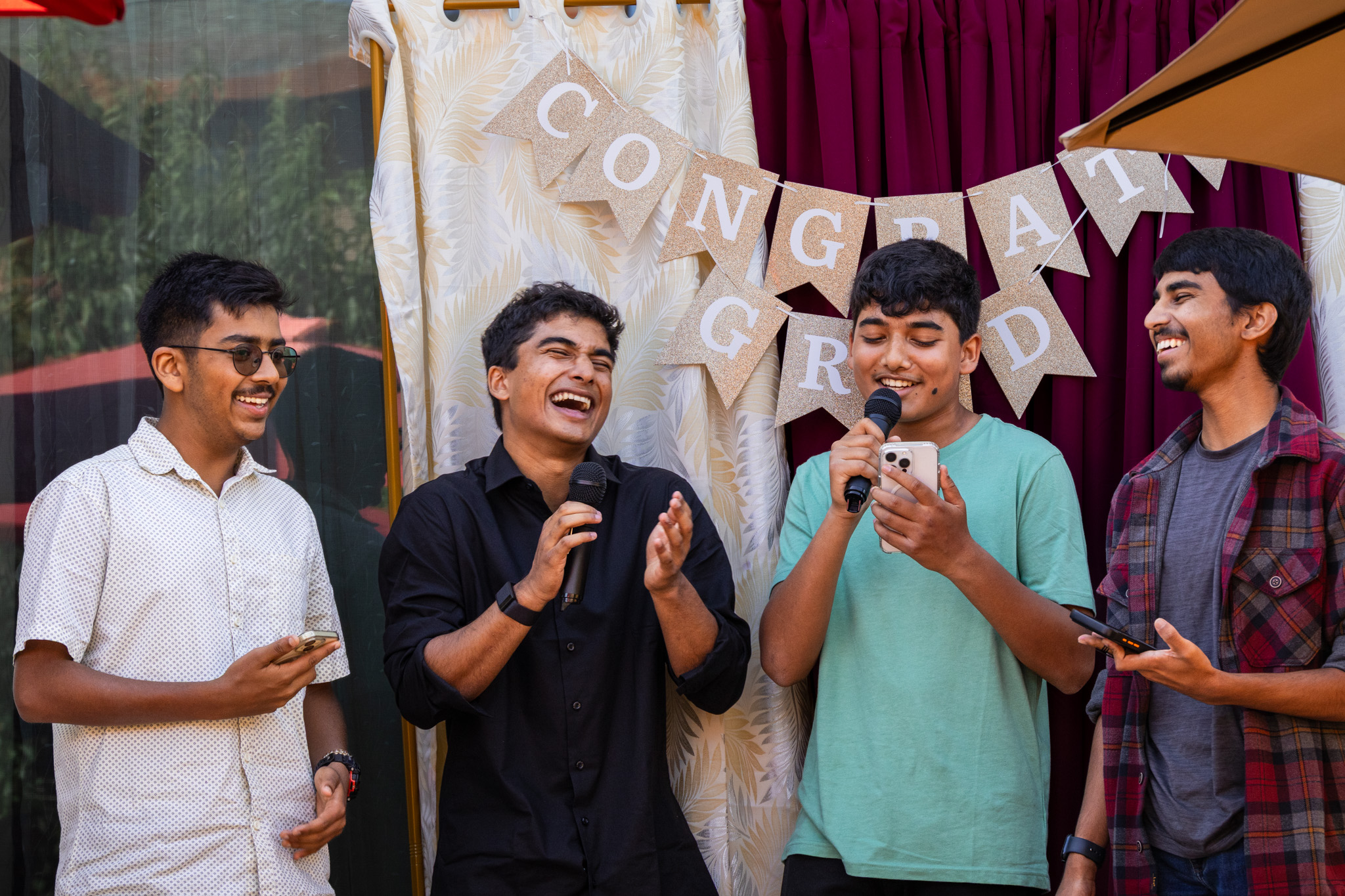 Group of four young men laughing and speaking at an event