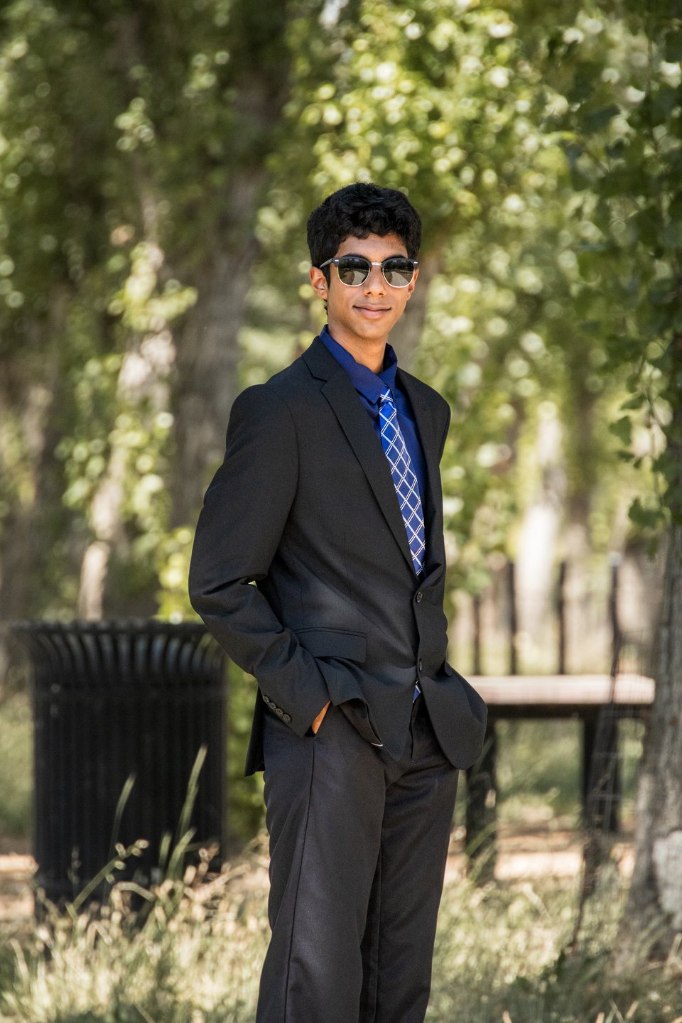 Solo prom portrait in black suit with blue patterned tie and sunglasses
