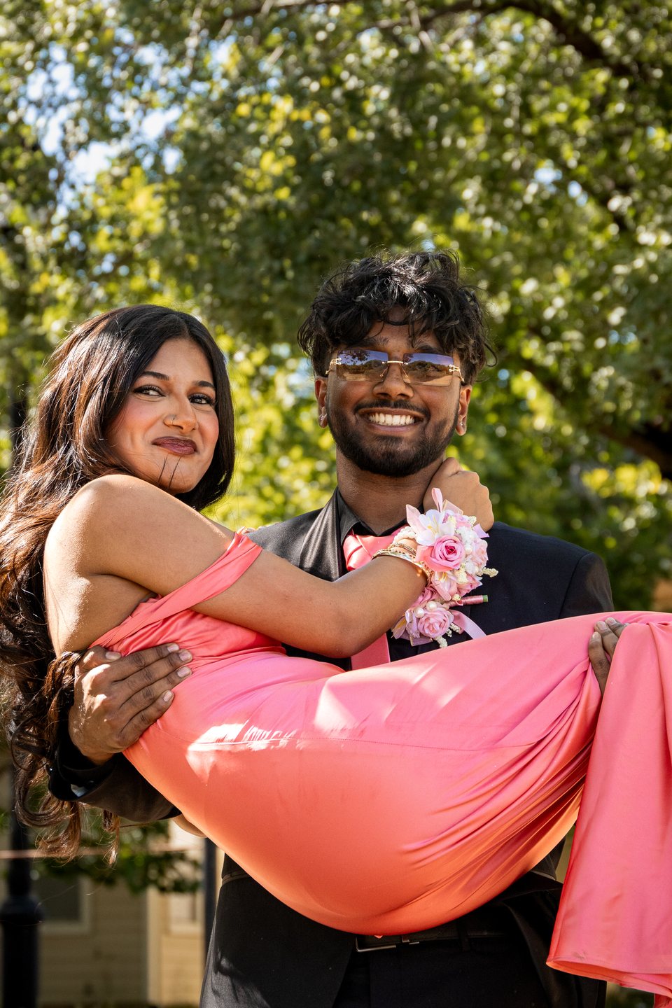 Prom couple smiling during a pink dress lift portrait