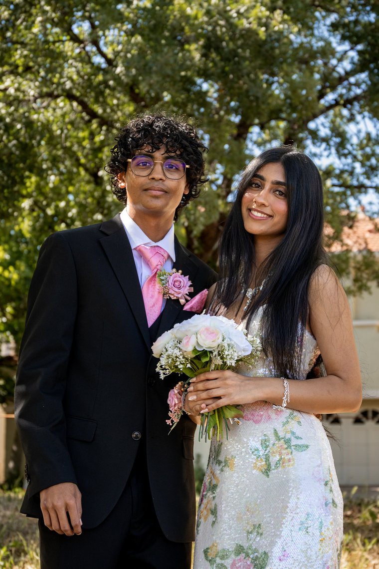 Prom couple facing each other with white floral bouquet